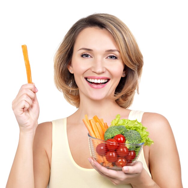 Bella giovane donna in buona salute con un piatto di verdure isolato su bianco.