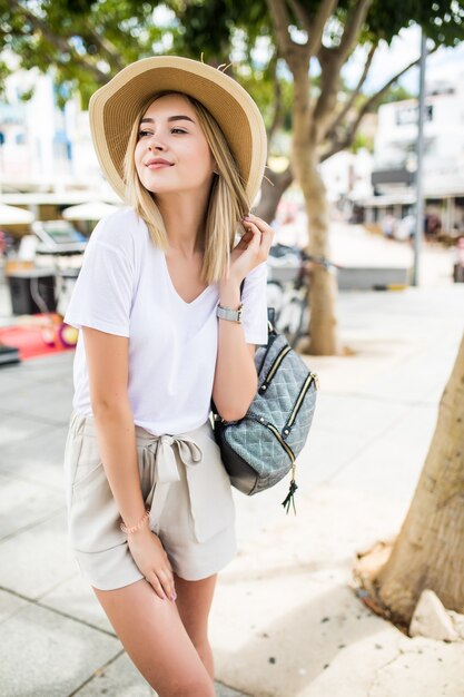 Bella giovane donna in cappello estivo a piedi in città.