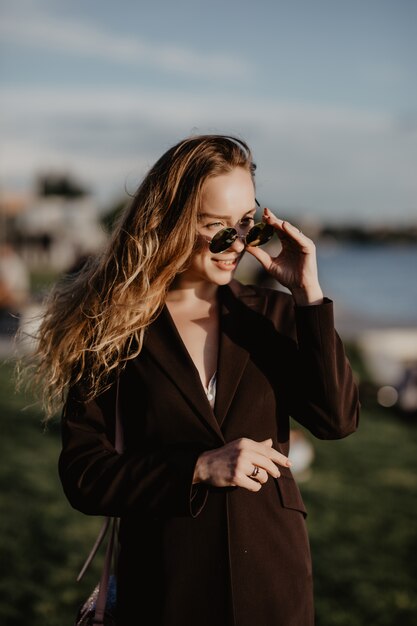 Bella giovane donna in occhiali da sole in città al tramonto