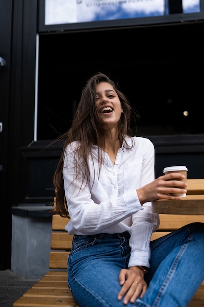 Bella giovane donna in street cafe beve caffè, all'aperto