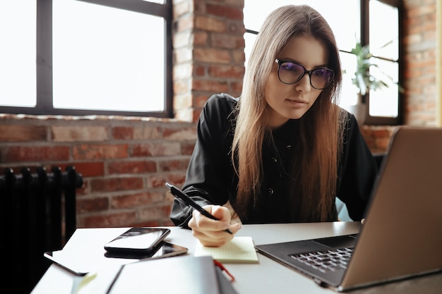 Bella giovane donna in ufficio a casa. Lavorare da casa. Concetto di telelavoro