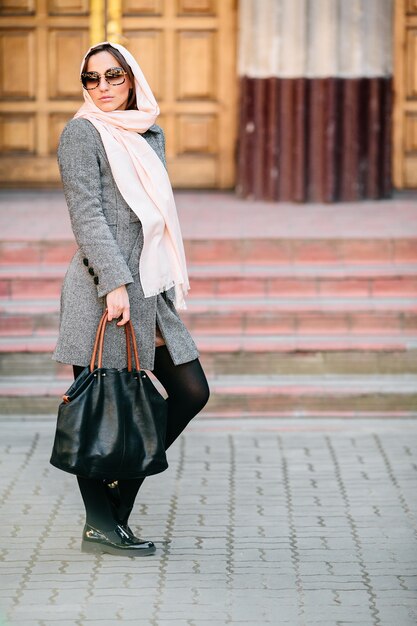 Bella giovane donna in un cappotto con una borsa in posa