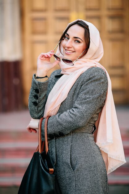 Bella giovane donna in un cappotto con una borsa in posa