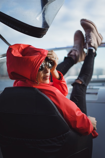bella giovane donna in un impermeabile rosso cavalca uno yacht privato. Stoccolma, Svezia