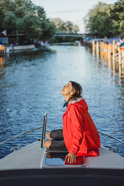 bella giovane donna in un impermeabile rosso cavalca uno yacht privato. Stoccolma, Svezia