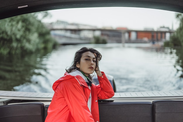 bella giovane donna in un impermeabile rosso cavalca uno yacht privato. Stoccolma, Svezia