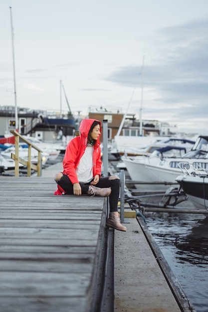 Bella giovane donna in un mantello rosso nel porto degli yacht. Stoccolma, Svezia