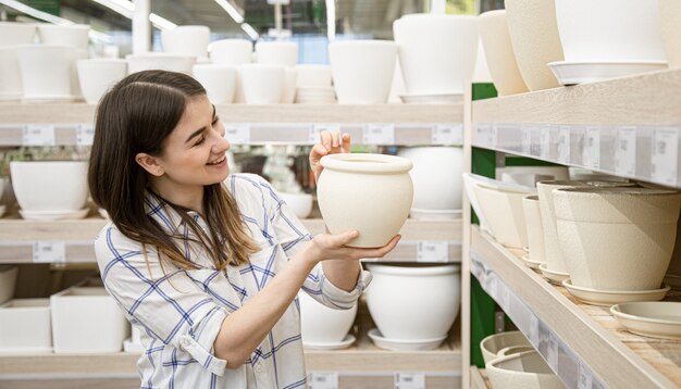 bella giovane donna in un negozio di fiori sceglie un vaso per fiori.