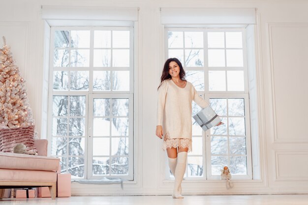 Bella giovane donna in vestito bianco che posa con il contenitore di regalo