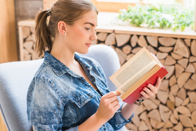 Bella giovane donna lettura libro in ufficio