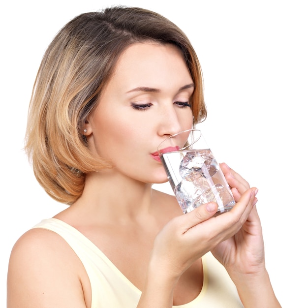 Bella giovane donna sorridente con un bicchiere d'acqua su bianco