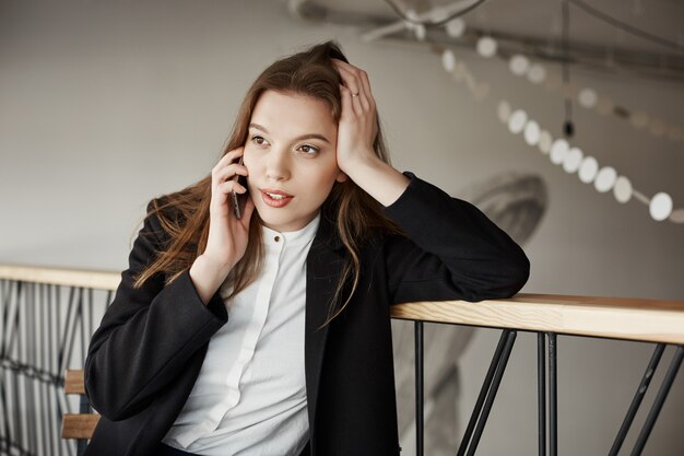 Bella giovane imprenditrice al caffè parlando per telefono