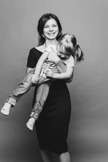 Bella giovane mamma con bambino piccolo che tiene e posa guardando la fotocamera Madre graziosa ed elegante che ama abbracciare il suo piccolo figlio Concetto di sguardo e relazione della famiglia del giorno dei genitori