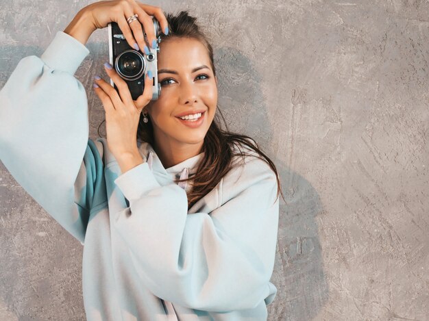 Bella giovane ragazza sorridente del fotografo che prende le foto usando la sua retro macchina fotografica.