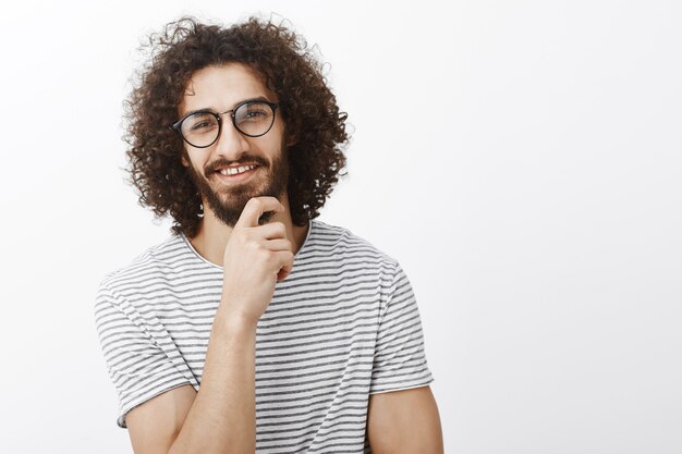 Bella idea, mi hai incuriosito. Ritratto di uomo adulto bello intelligente interessato con barba e capelli ricci in occhiali alla moda