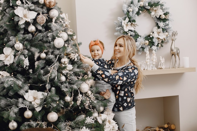 Bella madre con bambino. Famiglia in atmosfera natalizia. Persone che indossano albero di Natale.