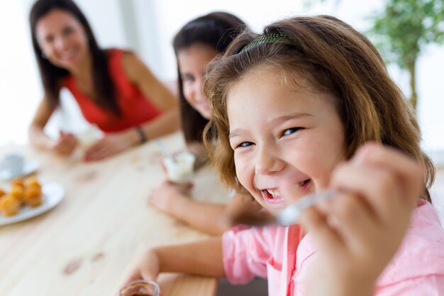 Bella madre e sua figlia mangiare iogurt a casa.