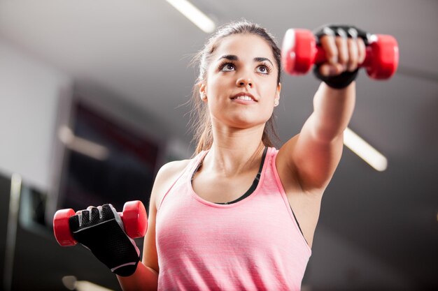 Bella mora che risolve con alcuni manubri in una palestra