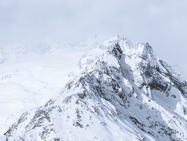 Bella panoramica delle montagne coperte di neve sotto un cielo nebbioso