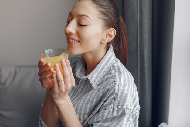 Bella ragazza a casa con il succo di oranhe