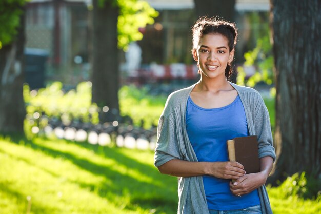 Bella ragazza africana allegra che legge il libro