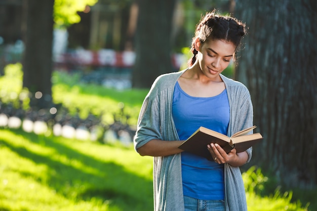 Bella ragazza africana allegra che legge il libro