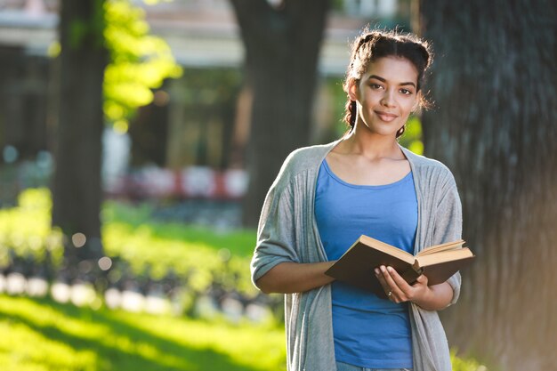 Bella ragazza africana allegra che legge il libro