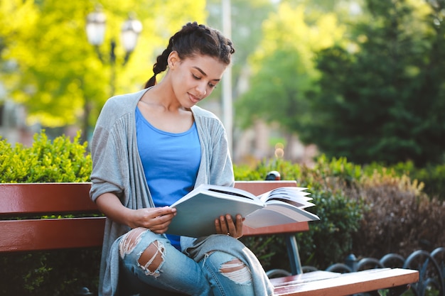 Bella ragazza africana Thouhtful che legge il libro