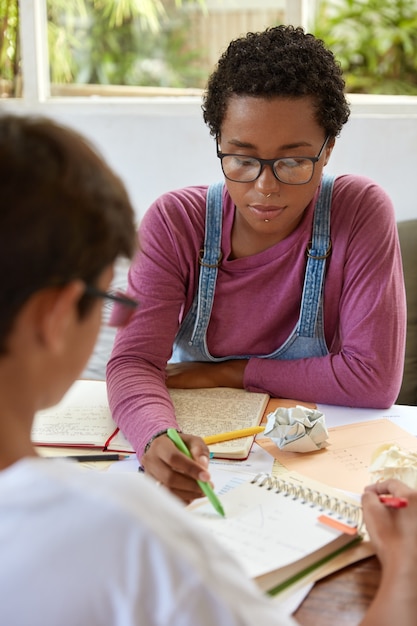 Bella ragazza alla moda cerca di aiutare il fratello minore che ha problemi con la matematica