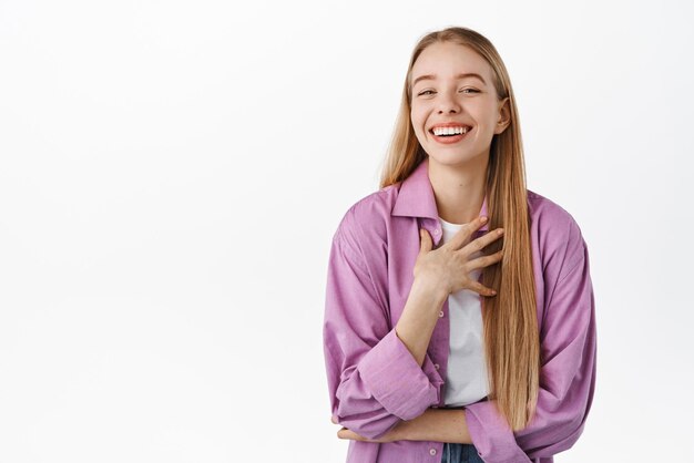 Bella ragazza autentica ridendo sorridente denti bianchi e guardando felice scherzando e divertendosi in piedi su sfondo bianco