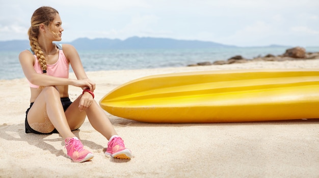 Bella ragazza bionda con corpo atletico rilassante dopo un lungo periodo, trascorrendo le vacanze nel paese tropicale.