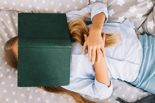 Bella ragazza che dorme con un libro sul viso