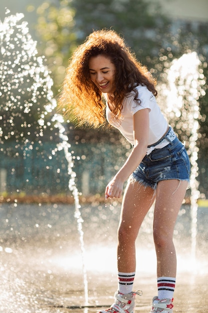 Bella ragazza che gode la sua giornata mentre gioca con l'acqua