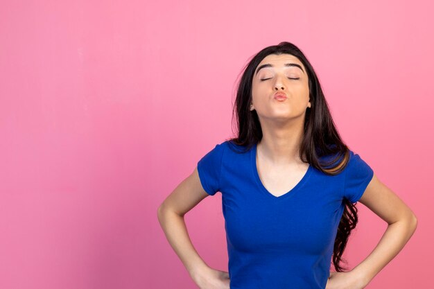 Bella ragazza che invia un bacio alla fotocamera sullo sfondo rosa Foto di alta qualità