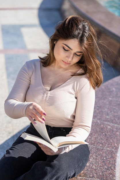 Bella ragazza che legge il suo libro al parco Foto di alta qualità