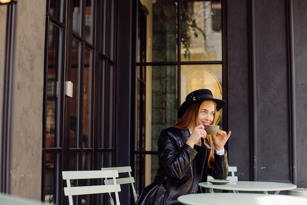 Bella ragazza che mangia caffè al caffè