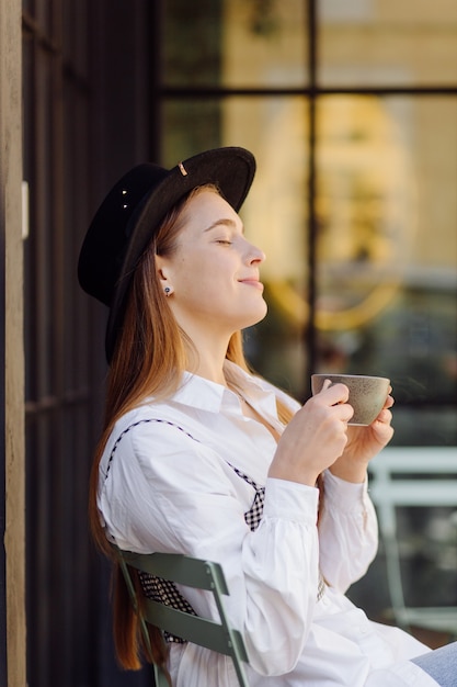 Bella ragazza che mangia caffè al caffè