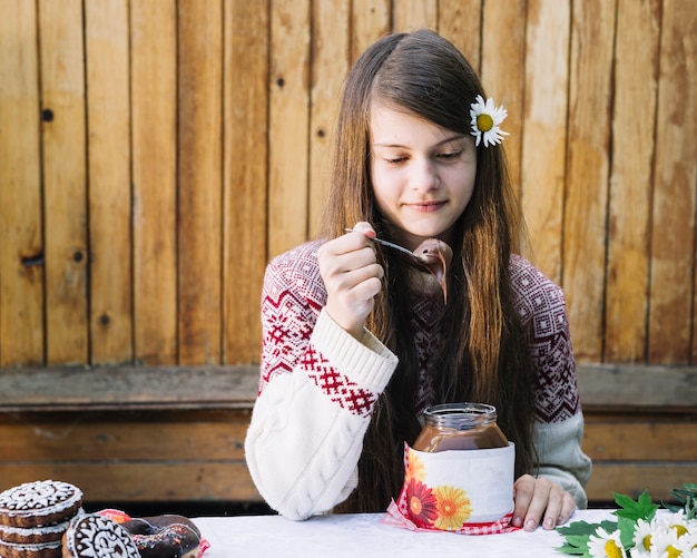 Bella ragazza che mangia cioccolato fuso in vaso sul tavolo