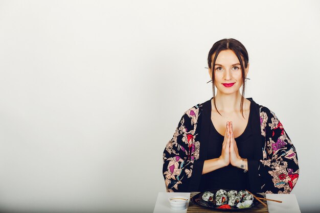 Bella ragazza che mangia un sushi in uno studio