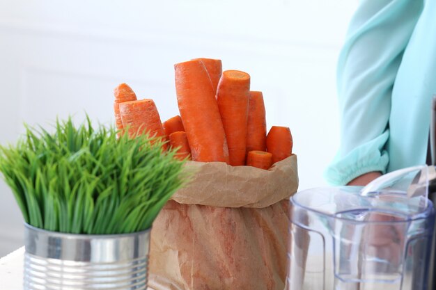 Bella ragazza che produce il succo di carota