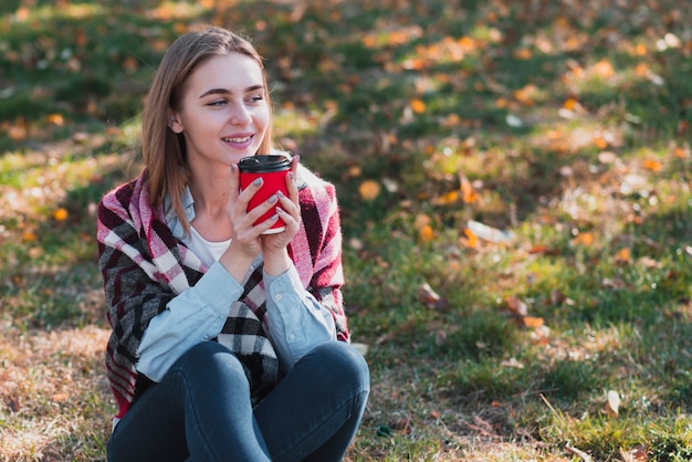 Bella ragazza che tiene una tazza di caffè e distogliere lo sguardo