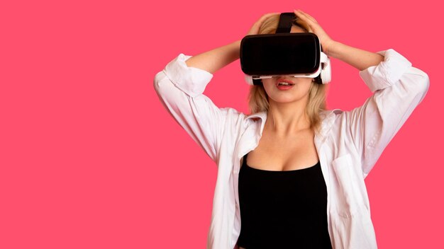 Bella ragazza con gli occhiali VR su uno sfondo rosa nella realtà virtuale