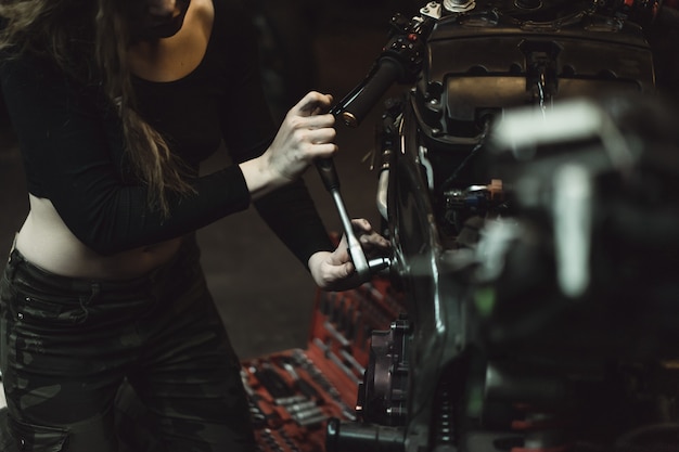 bella ragazza con i capelli lunghi nel garage di riparare una moto