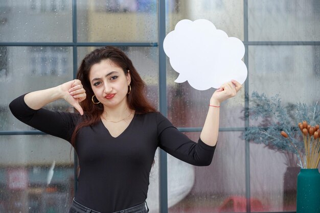 Bella ragazza con una bolla di idee a forma di nuvola e un gesto con il pollice verso il basso Foto di alta qualità
