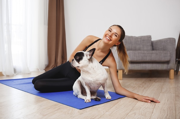 Bella ragazza di forma fisica che si siede sul pavimento con il cane