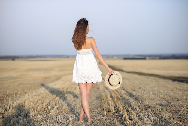 Bella ragazza elegante in un campo di grano in autunno