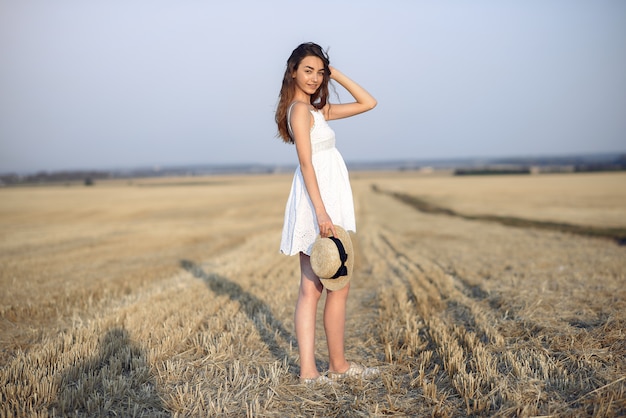 Bella ragazza elegante in un campo di grano in autunno