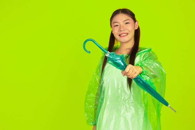 bella ragazza felice, con indosso abiti verdi, ombrello e cappotto, giornata di pioggia.