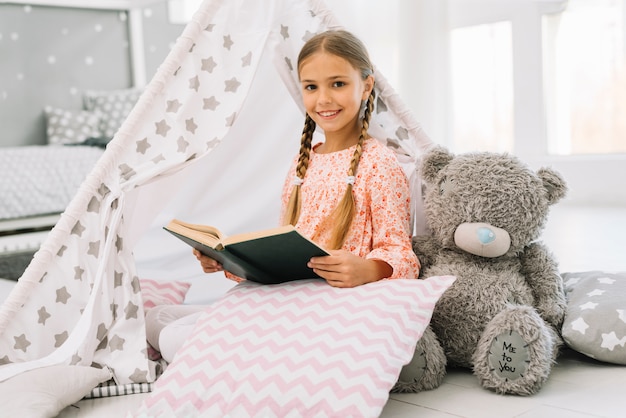 Bella ragazza felice in posa con un libro