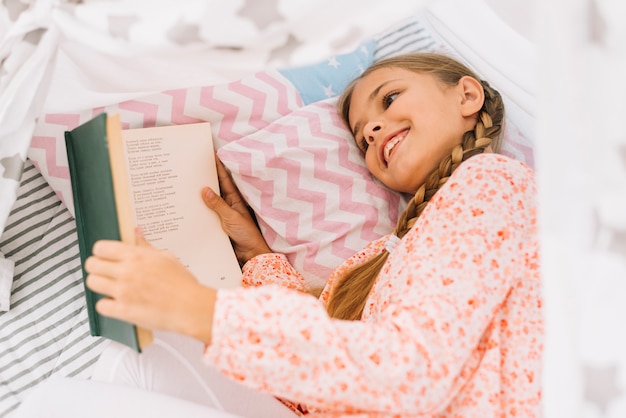 Bella ragazza felice in posa con un libro